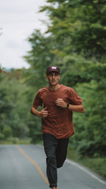Man jogging on road surrounded by trees