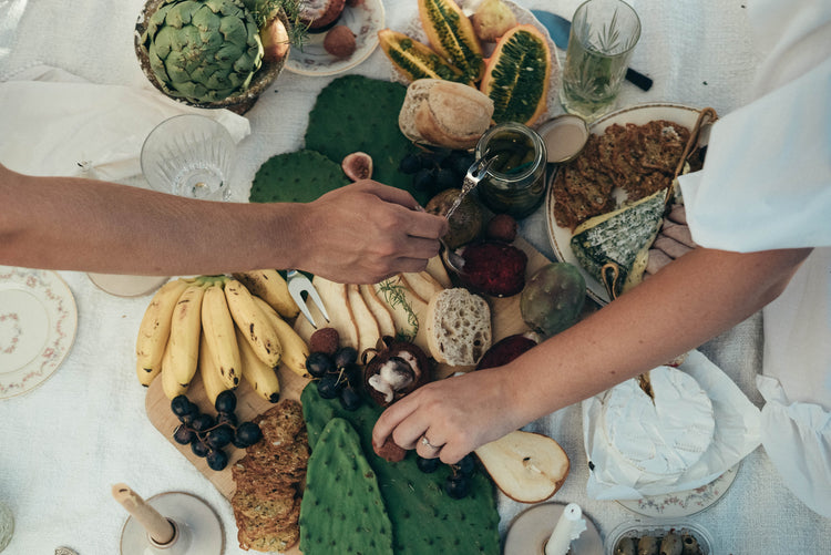 People getting food from a spread of healthy cheeses and fruits