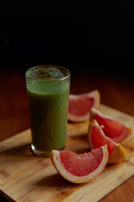 A glass of green smoothie with slices of grapefruit