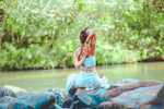 A woman practicing self love by stretching in nature, in front of a lake and trees