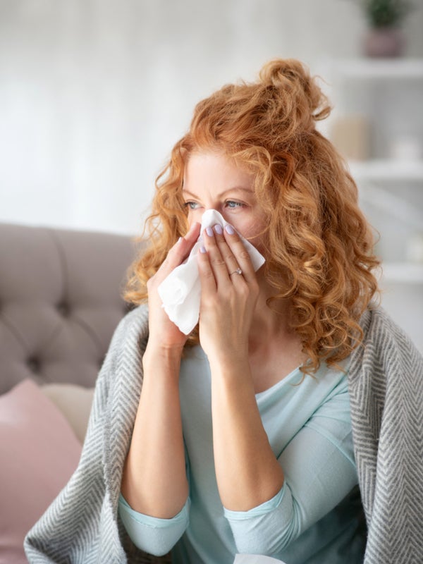 Woman having cold, blowing her nose