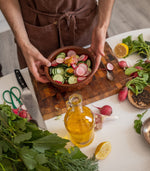 Person making salad with radishes, cucumbers, and lemons