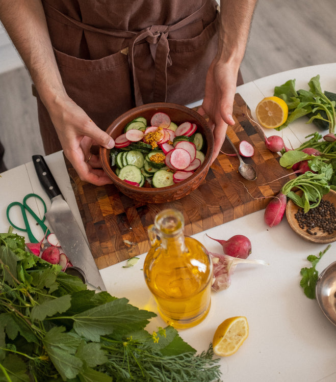 Person making salad with radishes, cucumbers, and lemons