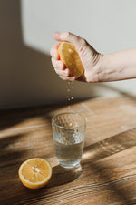 Person squeezing lemon into cup of water
