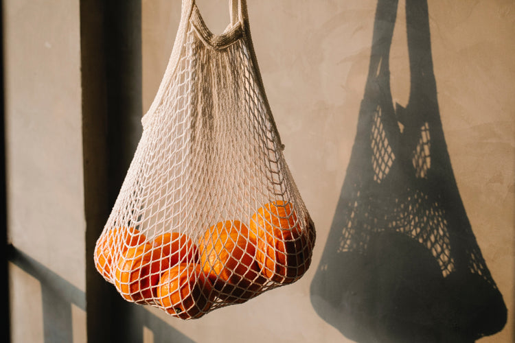 A mesh grocery bag full of oranges, which are full of Vitamin C