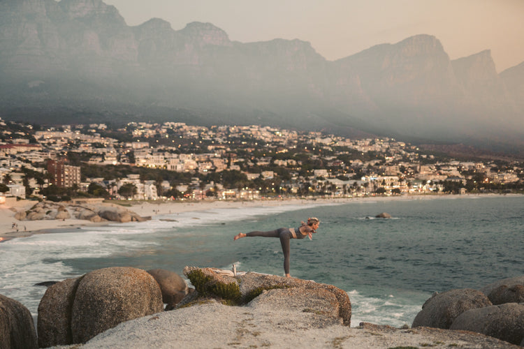 Woman practicing yoga on beach cliff