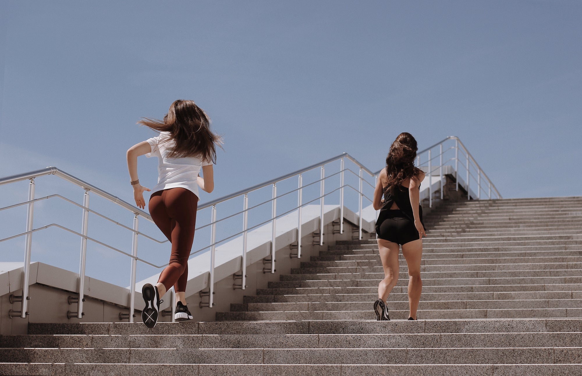 Two women exercising, running up stairs
