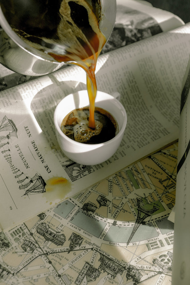 Coffee being poured in cup on top of paper map