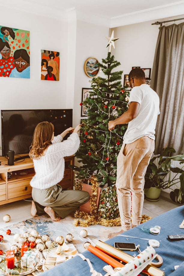 Couple decorating Christmas tree in their home